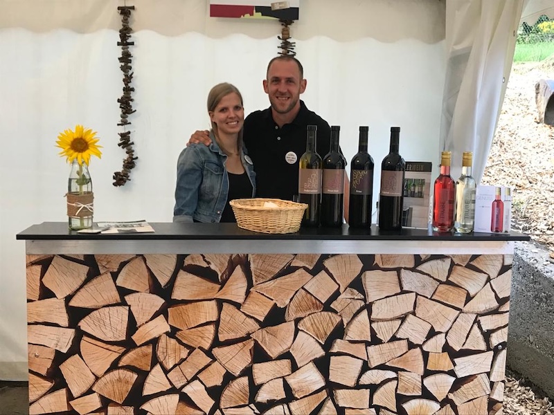 Dominik und Manuela Simmler bei der Weindegustation am Lindenhof in Buchberg – beide lachen in die Kamera, Gäste genießen regionale Weine