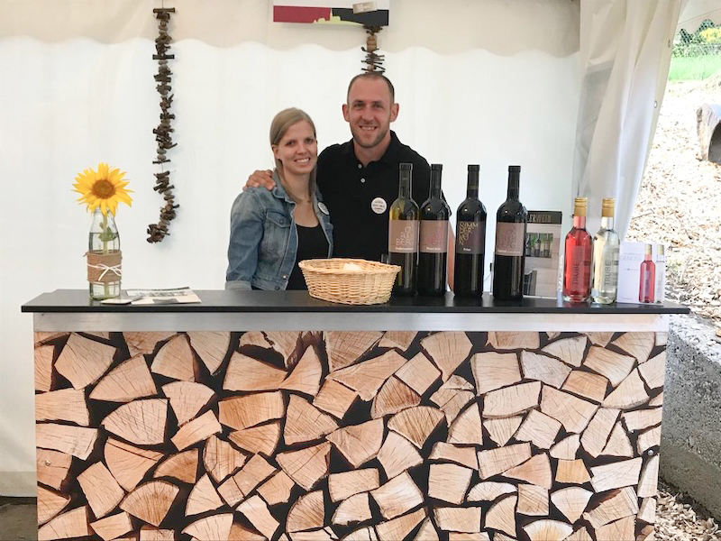 Dominik und Manuela Simmler bei der Weindegustation am Lindenhof in Buchberg – beide lachen in die Kamera, Gäste genießen regionale Weine